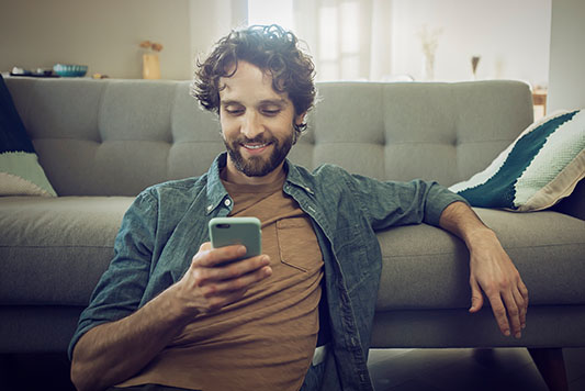 Trader checking single stock futures positions on the NinjaTrader mobile app from his couch