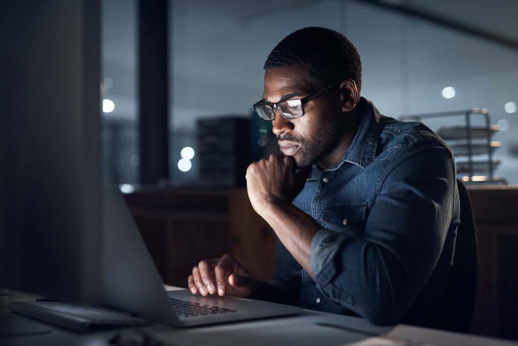 Trader working on a laptop in a dark office